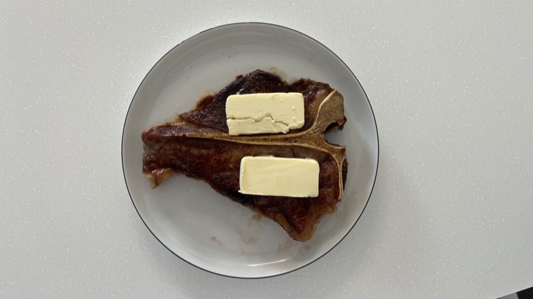 A T-bone steak with two thick slabs of butter on top