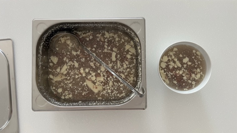 A big container and a bowl of beef broth, with the fat set on top