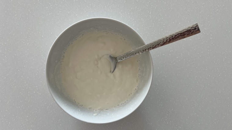 A bowl of thinned sour cream with a spoon