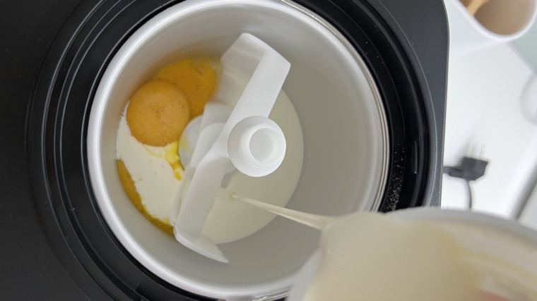 Egg yolks and cream being poured into an ice cream maker